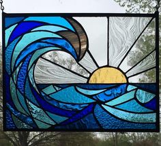 a stained glass window with waves and sun in the sky on it's side