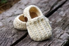 a pair of crocheted baby shoes sitting on top of a wooden table