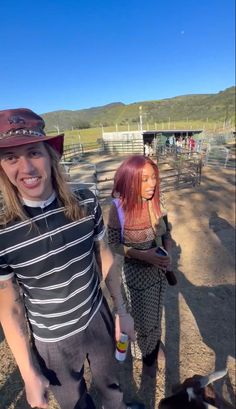 two people standing next to each other in front of a fence with animals on it