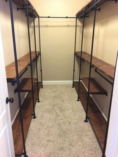 an empty walk in closet with wooden shelves and metal rails on the wall, along with carpeted flooring