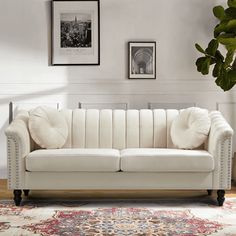 a white couch sitting on top of a wooden floor next to a potted plant