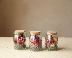 three jars filled with flowers sitting on top of a table