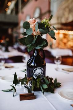 flowers in a vase on a table with plates and napkins at a wedding reception