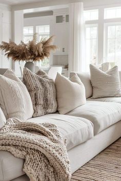 a living room filled with lots of white couches and pillows on top of each other