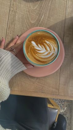 a person sitting at a table with a cup of coffee in front of their feet