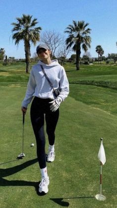 a woman walking across a green covered golf course