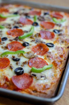 a pizza with pepperoni, black olives and green peppers