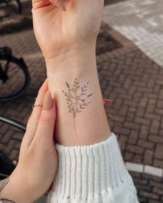 a woman's wrist with a small flower tattoo on the left side of her arm