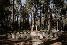 an outdoor ceremony setup with white chairs and trees in the background at a wedding venue