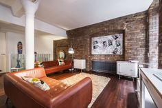 a living room filled with furniture next to a brick wall