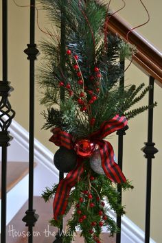 a christmas tree with red and black bows on it's banisters in front of stairs