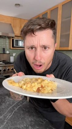 a man holding a plate with food on it in front of his face and looking surprised at the camera