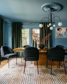 a dining room with blue walls, chairs and a rug on the floor in front of it