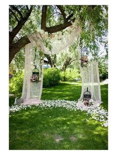 an outdoor wedding setup with flowers and birdcages on the grass under a tree