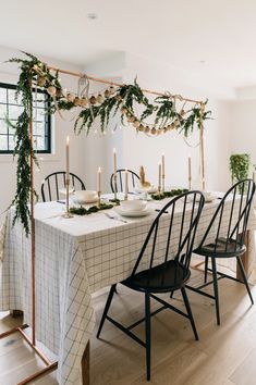 a dining room table decorated with greenery and candles