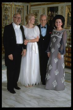 four people in formal wear standing next to each other