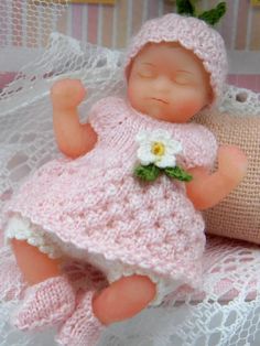 a baby doll laying on top of a white blanket