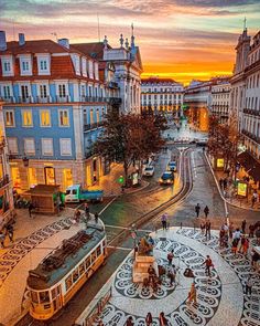 an aerial view of a street with people walking and riding on the sidewalks at sunset