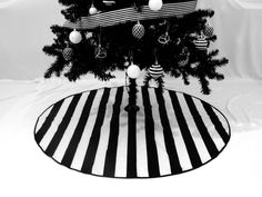 a black and white photo of a christmas tree on a striped rug with ornaments hanging from it