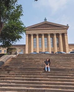 a woman sitting on some steps in front of a building