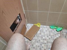 a person standing in front of a shower door with their feet on the floor next to them