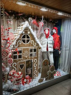 two people standing in front of a window with gingerbread house and candy canes