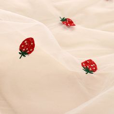 two red strawberries are embroidered onto white fabric