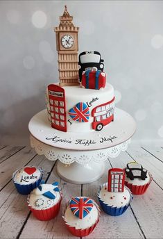 a three tiered cake with cupcakes in the shape of london and big ben