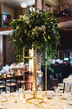 an elegant centerpiece with greenery and candles is displayed on a table at a wedding reception