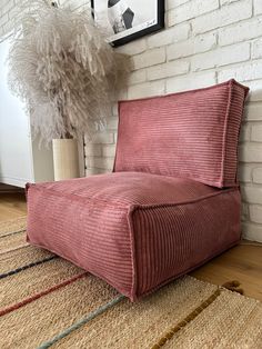 a red chair sitting on top of a rug next to a white brick wall