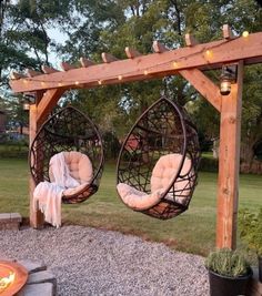 two hanging chairs in front of a fire pit with lights on the top and bottom