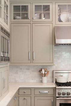 a kitchen with gray cabinets and white counter tops in shades of grey, brown, and beige