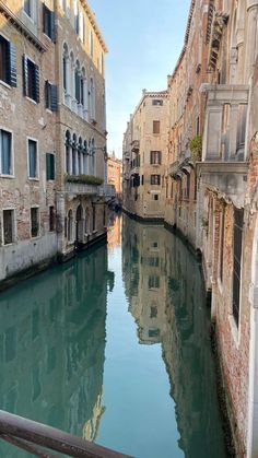 a narrow canal with buildings on both sides and water running through the middle, surrounded by windows