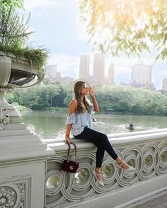 a woman is sitting on a bridge with her hand in her mouth and looking up at the sky