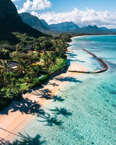 an aerial view of a tropical beach with palm trees and mountains in the back ground