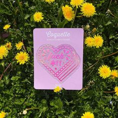 a pink sticker with the words love me on it surrounded by dandelions