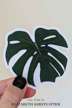 a person holding up a green leaf sticker