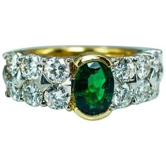 an emerald and diamond ring with two rows of diamonds