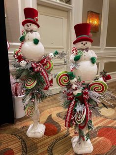 two snowmen with candy canes and hats on their heads are standing next to each other