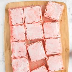 cubes of pink cake sitting on top of a wooden cutting board