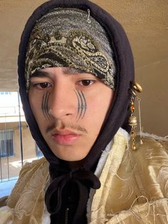 a young man with his face painted like a snake and wearing a bandanna around his head