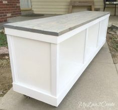 a white storage bench sitting on top of a sidewalk