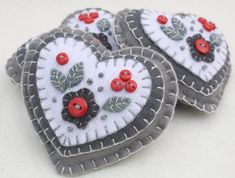 three felt hearts with red buttons and leaves on them are sitting next to each other