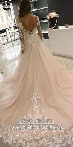 a woman in a wedding dress looking at the back of her gown, with flowers on it