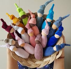 a person holding a basket filled with small stuffed toy animals in it's hands