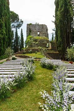 an outdoor ceremony set up with rows of pews and flowers in the foreground