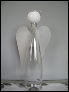 a clear glass vase with an angel decoration on the top and two white flowers in the middle