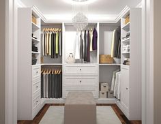 a walk in closet with white cabinets and drawers