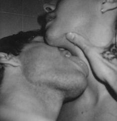 black and white photograph of man kissing woman's face in shower stall with tiled wall