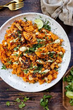 a white plate topped with rice covered in sauce and garnished with cilantro